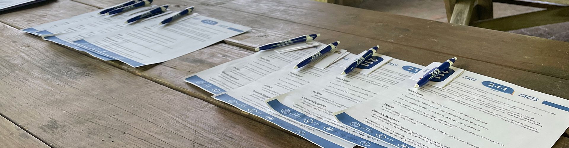 A wooden picnic table holds sign-up sheets with pens.